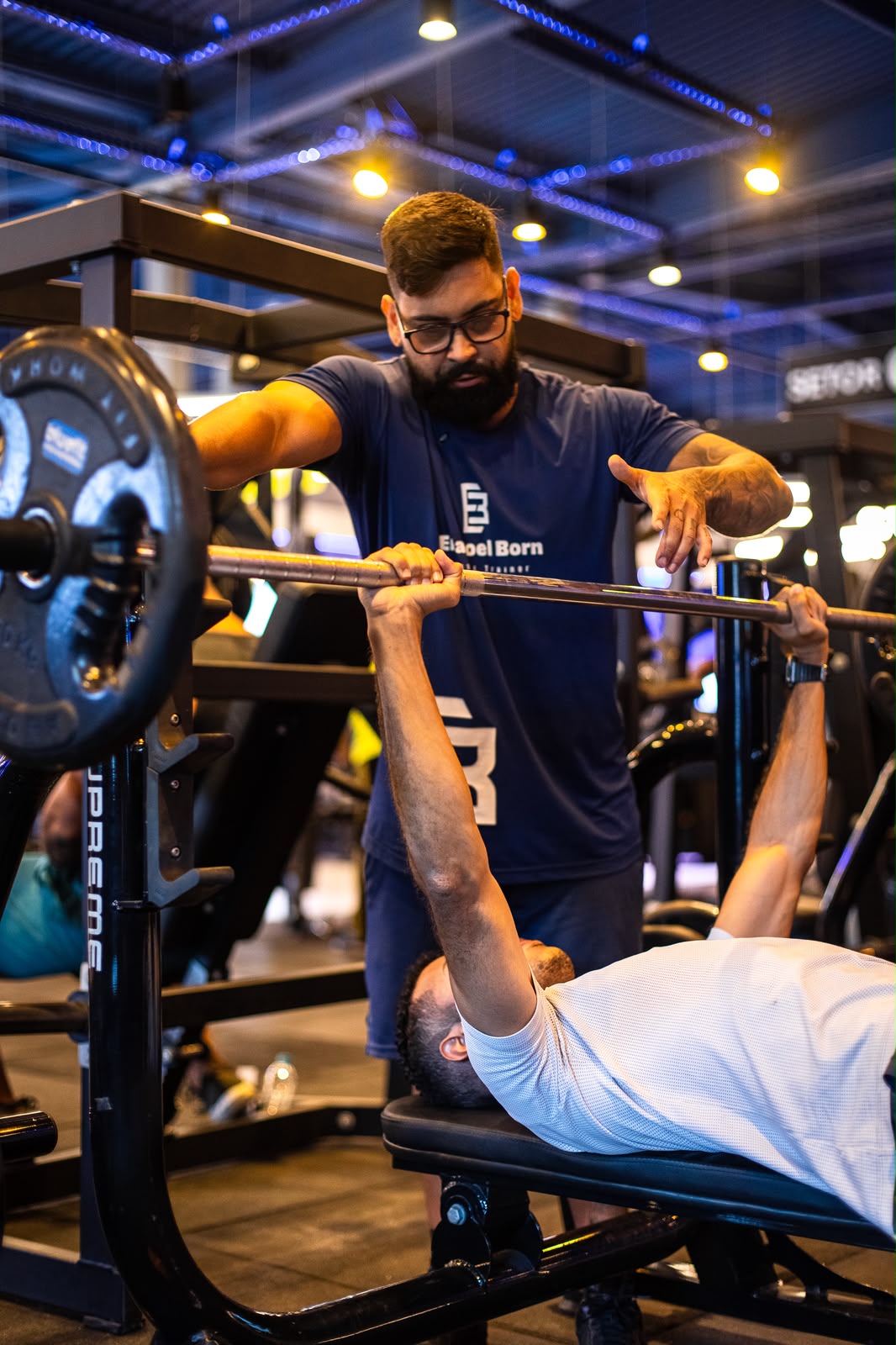 Personal trainer assistindo aluno no supino